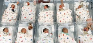 Ten babies wrapped in similar blankets in hospital nursery